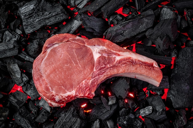 Photo raw steak on hot barbecue coals