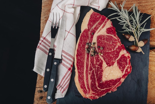 Raw steak on pizarra dish isolated on black background.