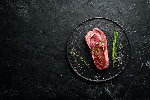 Raw Steak Ribeye On a black stone table Top view Free space for your text
