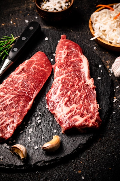 Raw steak on a stone board On a black background