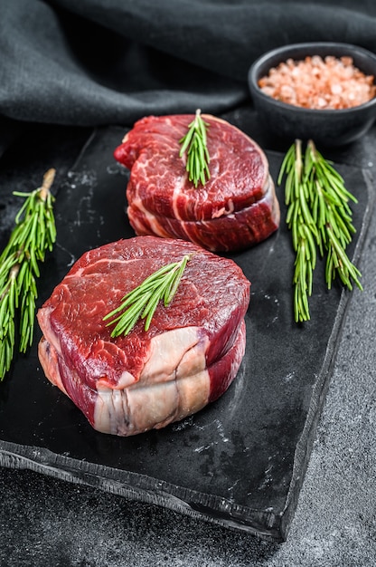 Raw steak Tenderloin fillet on a stone board. Black surface. Top view.