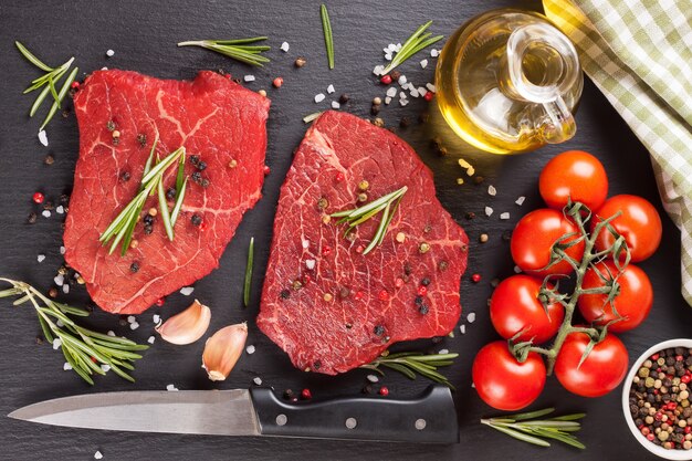 Raw steak with knife,  spices and ingredients for cooking.