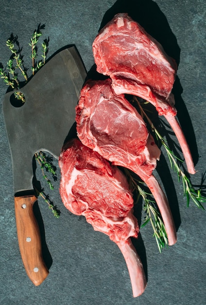 Raw steak with a meat cleaver on a dark stone background.