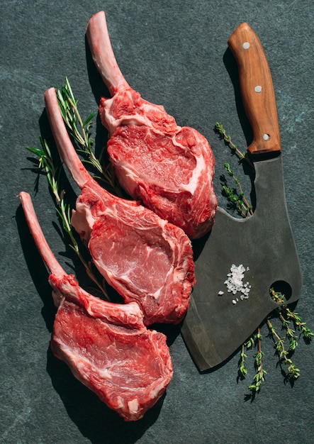 Raw steak with a meat cleaver on dark stone.