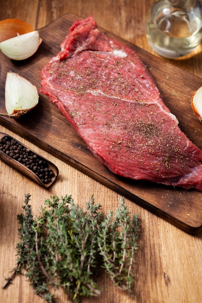 Raw steak with rosmary , salt and and peper on wooden table. Meat seasoning. Organic food.