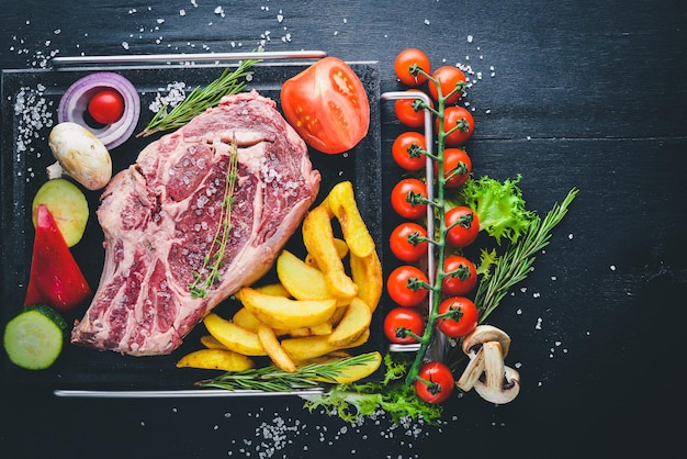 Photo raw steak with vegetables and sauce on a wooden background top view free space for your text