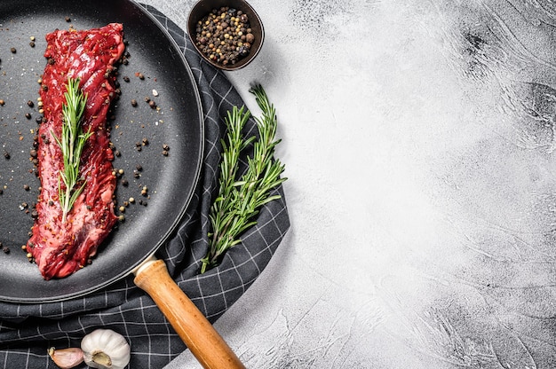 Raw strip vegas steak in a pan with cooking ingredients. Gray background