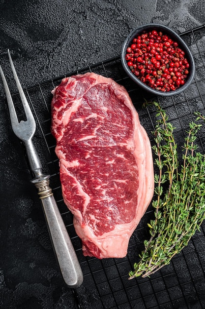 Raw striploin or New York beef meat steak ready for BBQ Black background Top view