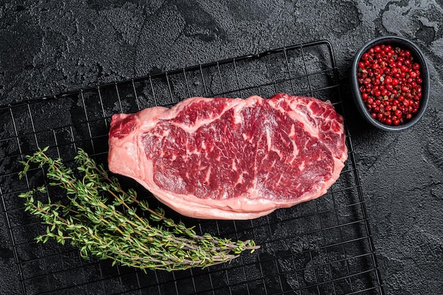 Raw striploin or New York beef meat steak ready for BBQ Black background Top view