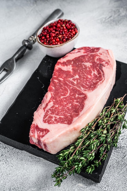 Raw striploin or new york strip steak on a marble board. White background. Top view.