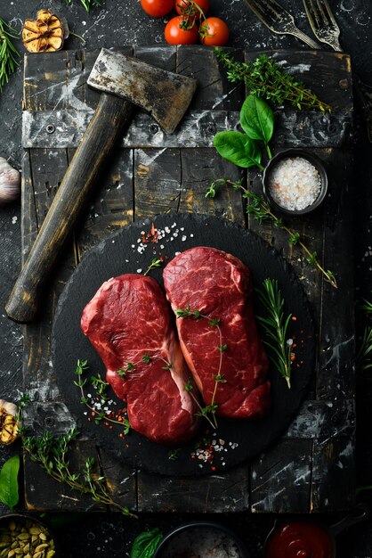 Raw striploin steak New York of beef on a board Top view On a black stone plate