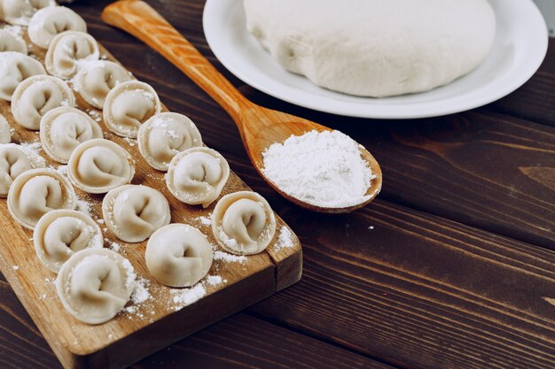 Raw stuffed russian dumplings on wooden cutting board