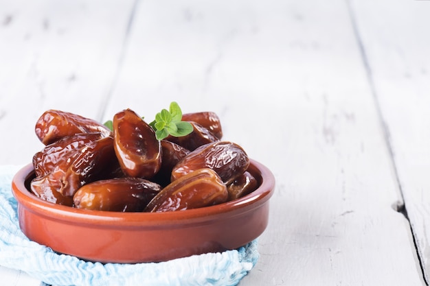 Raw sweet dry dates in a terracotta bowl