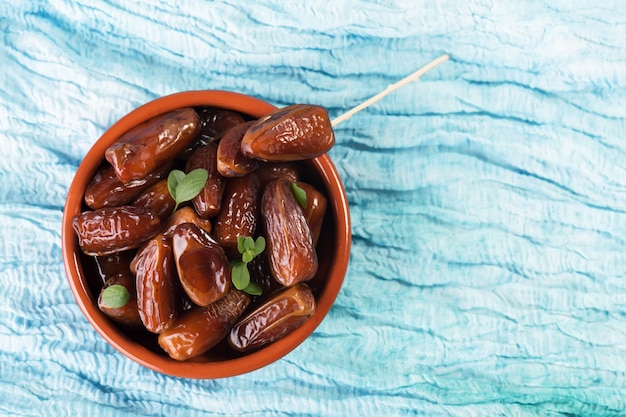 Datteri secchi dolci crudi in una ciotola di terracotta