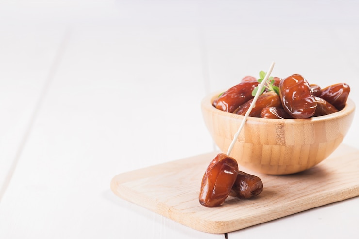 Photo raw sweet dry dates in a wooden bowl