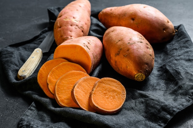 Patate dolci crude, igname biologico. il cibo della fattoria. sfondo nero.