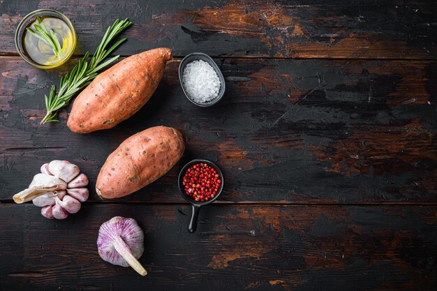 Raw sweet potatoes with herbs on a wooden table