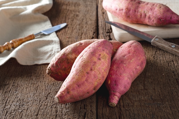 Raw sweet potatoes on a wooden table