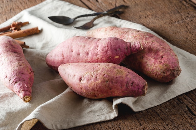 Raw sweet potatoes on a wooden table