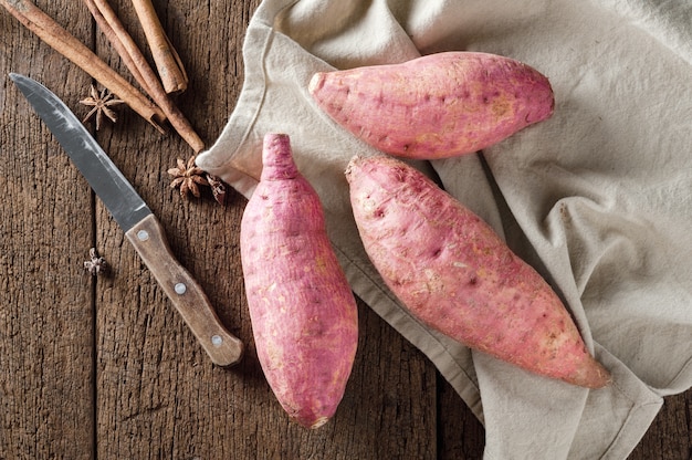 Raw sweet potatoes on a wooden table