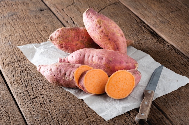 Raw sweet potatoes on a wooden table