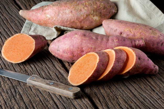 Raw sweet potatoes on a wooden table