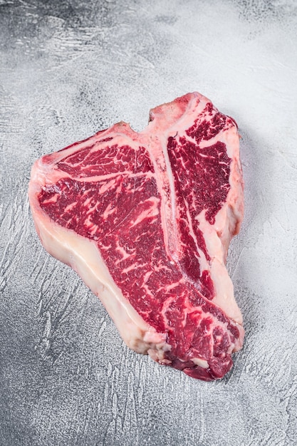 Raw T-bone or porterhouse Steak on kitchen table on white table. Top view.