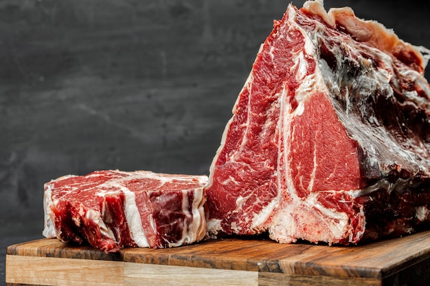 Raw T-bone steak cooking on stone table.