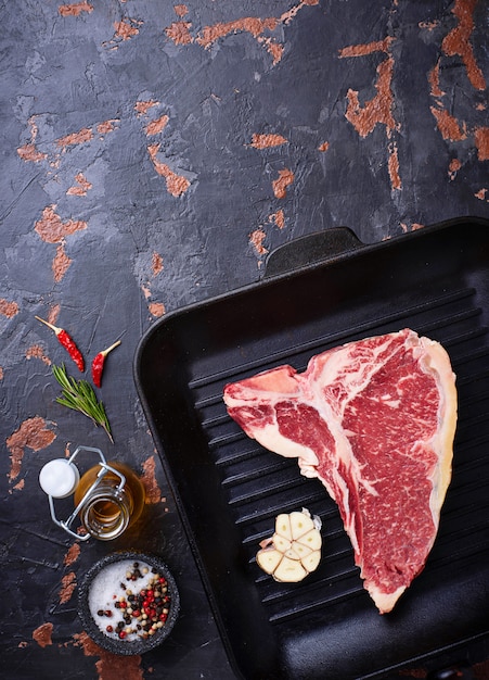 Raw T-bone steak on iron grill pan