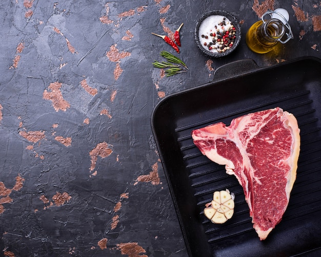 Raw T-bone steak on iron grill pan