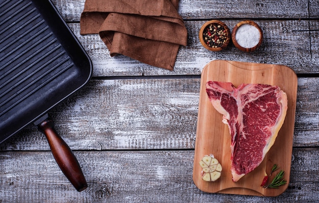 Raw T-bone steak and iron grill pan