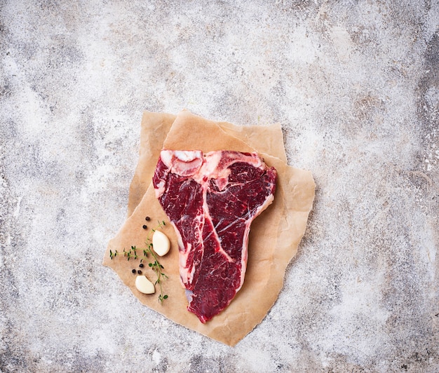 Raw T-bone steak with garlic and thyme 