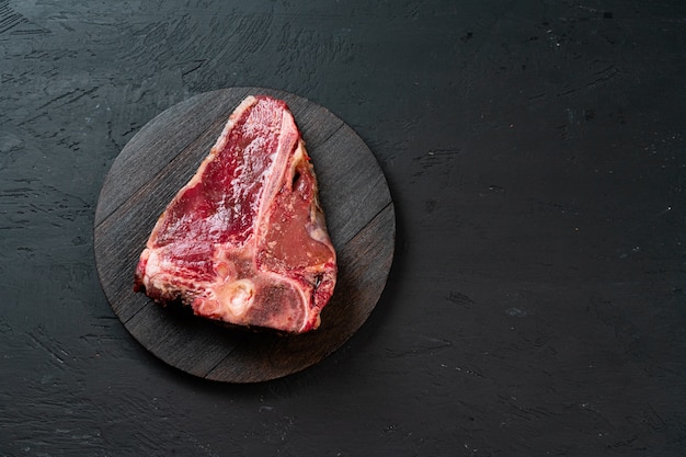 Raw T-bone steak with herbs on wooden board