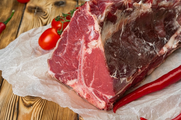 Raw T-bone steak with herbs on wooden board