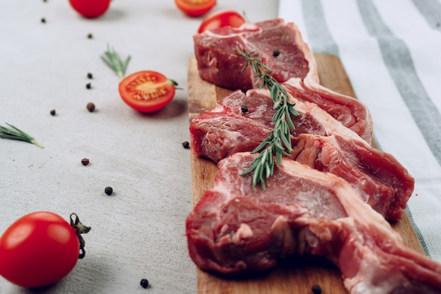 Raw t-bone steak on wooden cutting board on wooden table close up