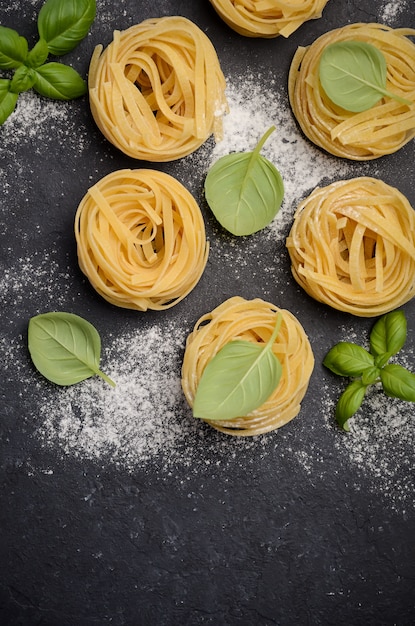 Raw tagliatelle pasta on the black concrete background.