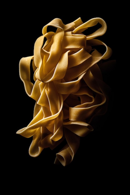 Raw tagliatelle pasta isolated on black background as package design element