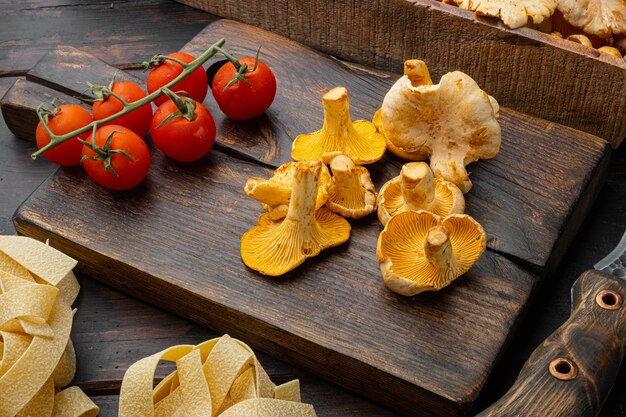 Photo raw tagliatelle with chanterelle mushrooms ingredients set, on old dark  wooden table background