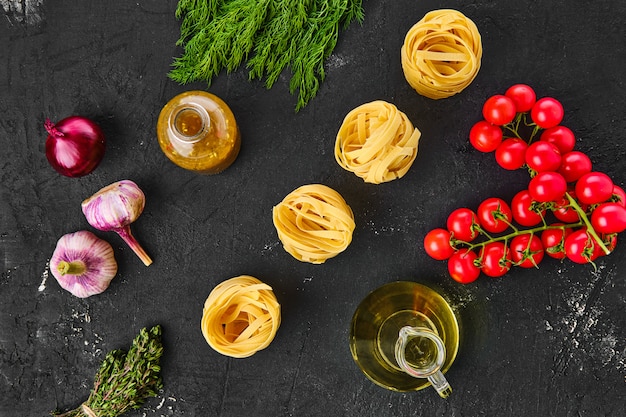 Raw tagliatelle with ingredients on a table