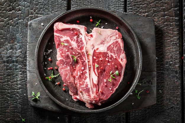 Raw tbone steak with salt pepper and rosemary