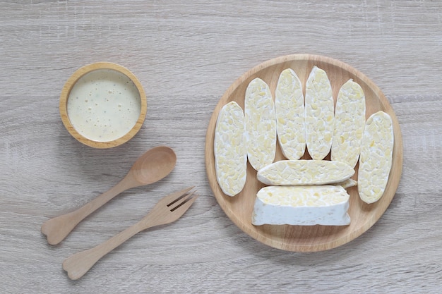 Tempeh crudo vista dall'alto del tempeh di ceci e del condimento per insalata in una ciotola su sfondo legnoso concetto di alimentazione sana