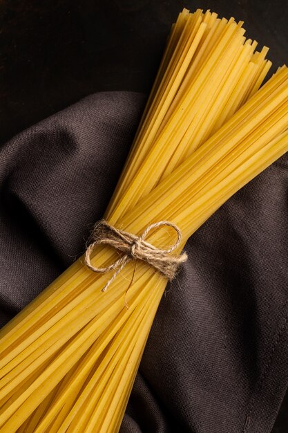 Raw tied noodles on a gray napkin on a dark background