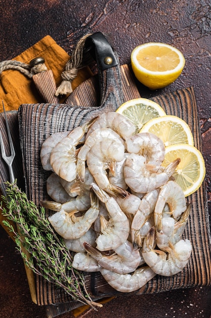 Raw tiger white shrimp prawn on board with herbs Dark background Top view