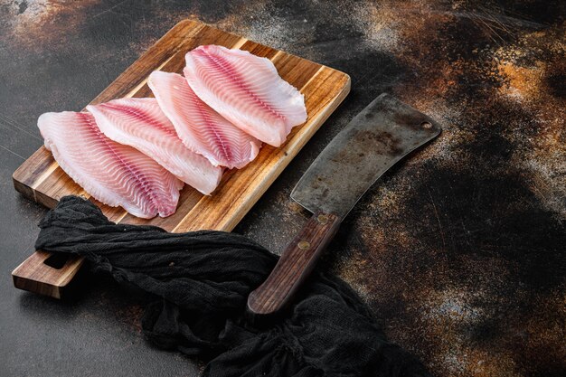 Raw tilapia fish fillet meat cuts, on old rustic background with copy space for text