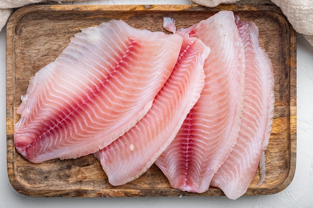 Сырые куски мяса филе рыбы тилапии, на белом фоне, вид сверху