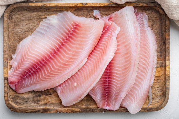 Raw tilapia fish fillet meat cuts, on white background, top view