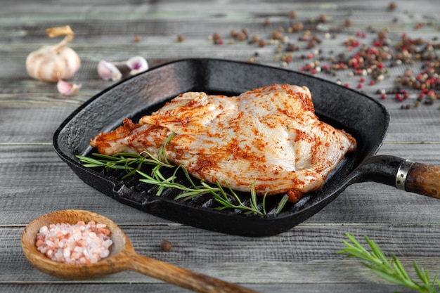 Raw tobacco chicken in spices in black grill pan, pepper