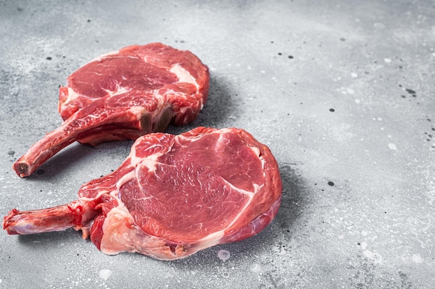 Raw Tomahawk beef (veal) steak on butcher table. Gray background. Top view. Copy space.