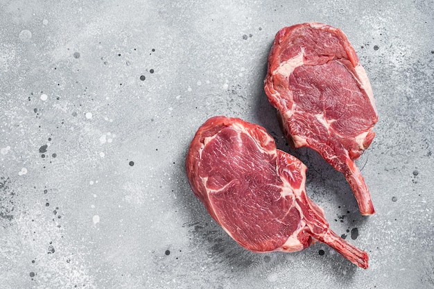 Raw Tomahawk beef veal steak on butcher table Gray background Top view Copy space