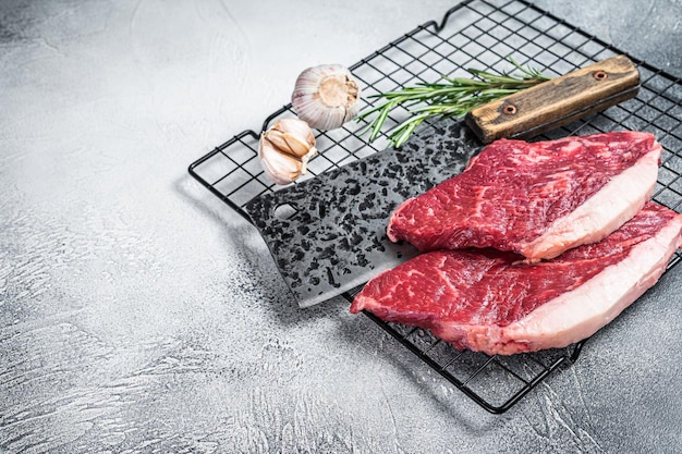 Raw top sirloin beef meat steak on a butcher cleaver cap rump\
steak white background top view copy space